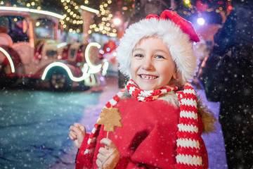 Child on christmas market. cute lovely girl in red hat standing at street