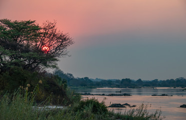 Sonnenuntegang am Cubango, Namibia, Angola, ein Boot setzt über