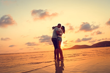 silhouettes in love romantic couple lovers hugging, smiling, touching, at sunset, sunrise on the...
