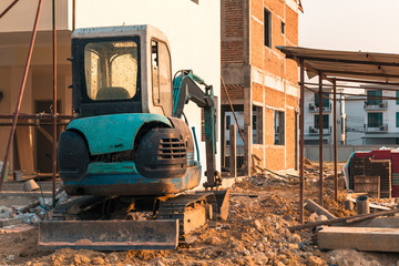 Fototapeta na wymiar Mini excavator on construction site.Excavator regulates the terrain around the house.