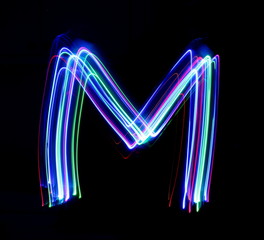 Long exposure photograph of a letter m in neon colour in an abstract swirl, parallel lines pattern...
