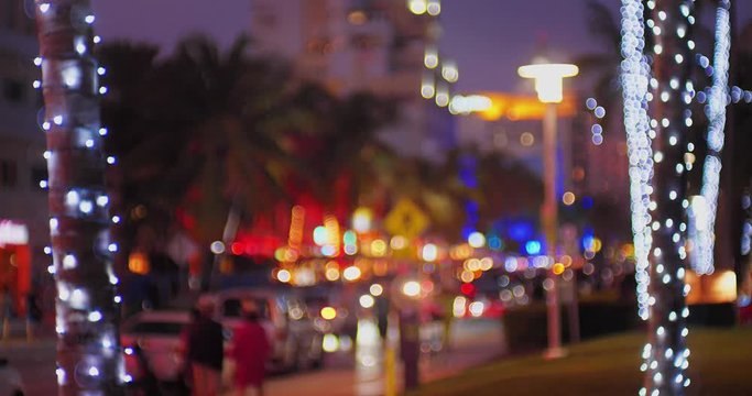 Nighttime glittery bokeh of traffic and Christmas lights along Ocean Drive in Miami Beach, Florida.  	