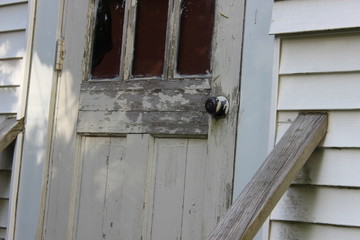 Old abandoned weathered boarded up historic country farmhouse with boarded up windows and peeling paint