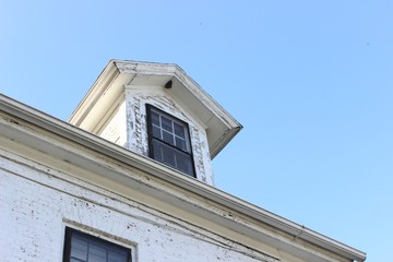 Old abandoned weathered boarded up historic country farmhouse with boarded up windows and peeling paint