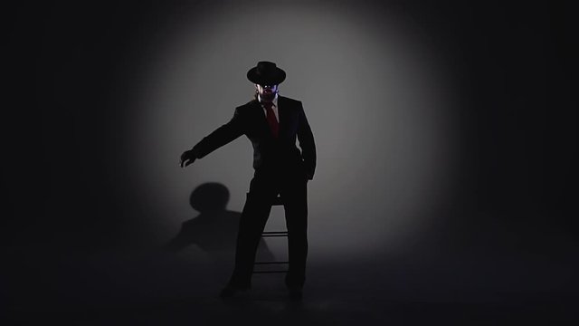 Elegant man in a black hat is dancing an erotic dance. Spotlight on a black background. Close up, slow motion.