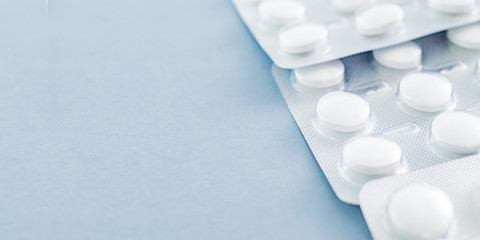 White pills in a blister on a blue background. Medical pharmacy concept