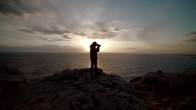 silhouette of a photographer on the beach and sunset. Outdoor photographer in a remote location during a picturesque sunset. 