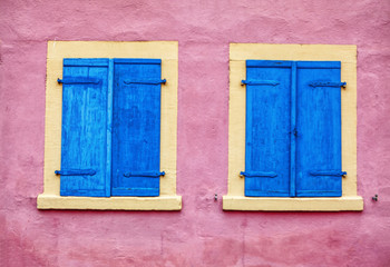 pink wall with wooden blue windows
