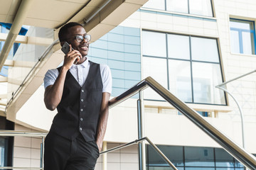 Young african american business man in suit and eyeglasses talking on the phone on the background of the business center