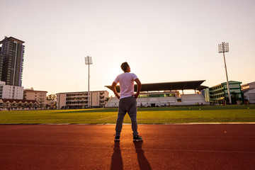 A sport man standing in racetrack at sport stadium with sunset. Sport concept.