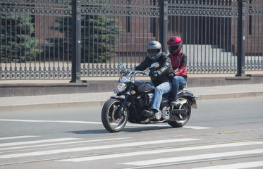 man and a woman on a motorcycle in helmets ride on a street