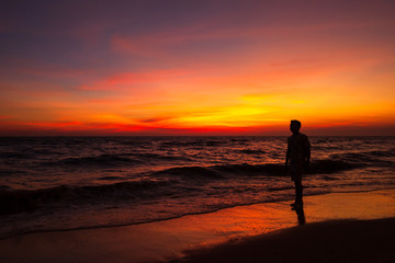 Fototapeta na wymiar silhouette a man stand on the beach and twilight sunset cloud.