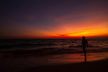 Fototapeta na wymiar silhouette a man stand on the beach and twilight sunset cloud.