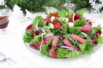 Holiday salad with roast beef on christmas decoration background