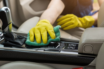 Cleaning service. Man in uniform and yellow gloves washes a car interior in a car wash