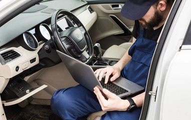 Obraz premium Professional car mechanic working in auto repair service. Computer video investigate. Engine diagnostics. Service station.