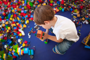 4 years boy building a tower with with interlocking plastic bricks