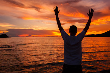 Happy Man with hands up on sandy beach watching Sea, mountain and cloud in the sea on sunset times. Background, close up