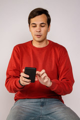 The guy in the red sweater is using a smartphone. Examines the image