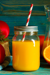 glass jar of fresh orange juice with fresh fruits on wooden table