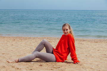 the blonde in the red walks along the beach of the sea coast