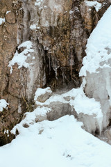 Closeup of small frozen waterfall and snowy rocks