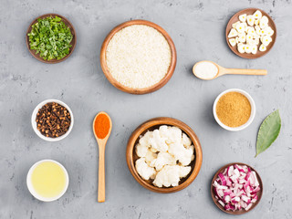Ingredients for cooking basmati rice: butter, salt, cloves, green herbs, masala, red onion, bay leaves, garlic, cauliflower, red chili pepper. Healthy eating concept