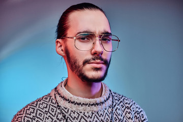 Sceptical tired man in glasses is posing for photographer at studio.