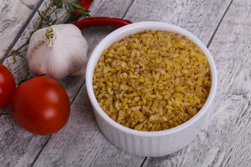 Raw bulgur in the bowl with tomatoes and garlic