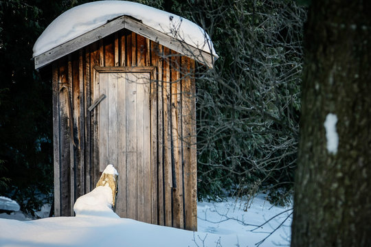 La cabane des toilettes en bois au fond du jardin sous la neige