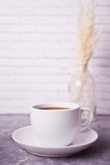 Close up of cup of coffee and brick white wall on the background. Copy space.