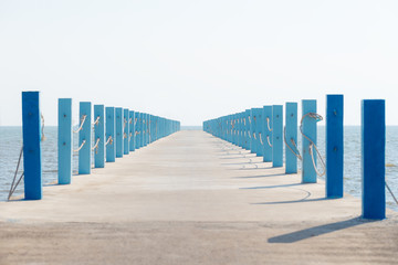 Cement walkway / path with pillar, post, pole in pastel color stretch into the sea
