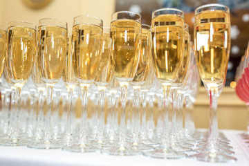 lot of blurred glasses with champagne on the reception party table on light background