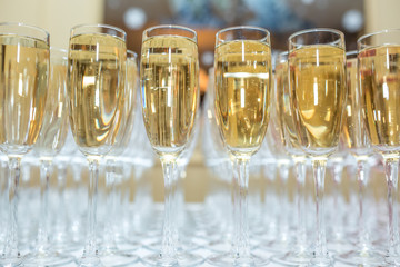 lot of blurred glasses with champagne on the reception party table on light background