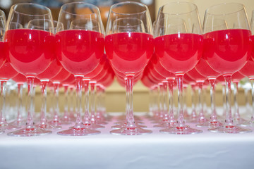 lot of blurred glasses with red wine on the reception party table on light background