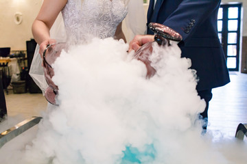 bride and groom make a cocktail of dry ice, alcohol and juice, glass with the effect of dry ice,blue cocktail with ice vapor, table with cocktails and dry ice
