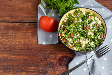 Tabbouleh  salad in a round plate on a wooden background.
