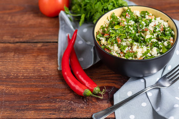 Tabbouleh  salad in a round plate on a wooden background.