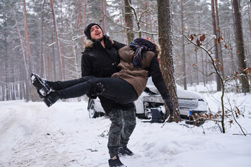 Man is holding injured woman after car crush in winter forest and screaming for help.