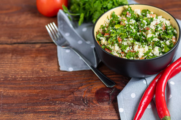 Tabbouleh  salad in a round plate on a wooden background.
