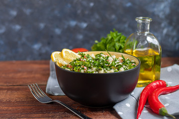 Tabbouleh  salad in a round plate on a wooden background.