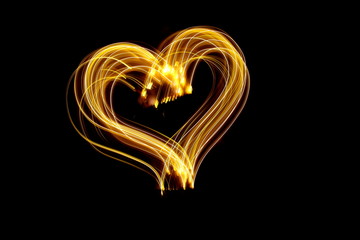 Long exposure photograph of a heart outline shape in gold neon colour in an abstract swirl,...