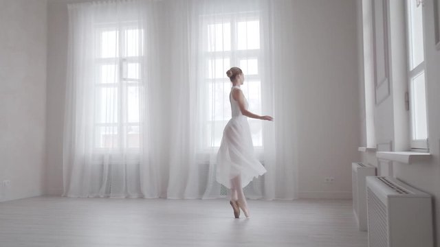 ballerina in a snow-white dress beautifully dances and spins on tiptoe