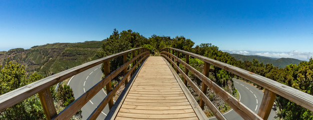 Pedestrian bridge across the main road. Relict forest on the slopes of the mountain range of the Garajonay National Park. Paradise for hiking. Fish eye lens shot panorama. La Gomera, Spain