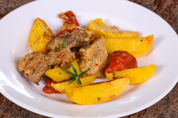 Baked pork meat with potao and tomato