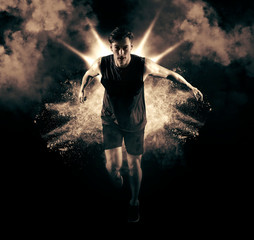 Fototapeta na wymiar Athletic man sprinter running on smoke background