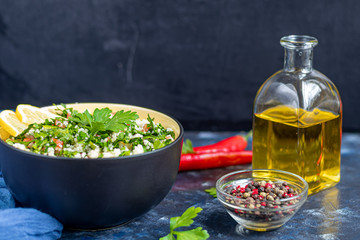 Tabbouleh salad in a round plate on a dark blue background.