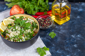 Tabbouleh salad in a round plate on a dark blue background.