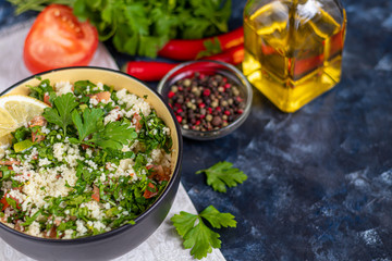 Tabbouleh salad in a round plate on a dark blue background.
