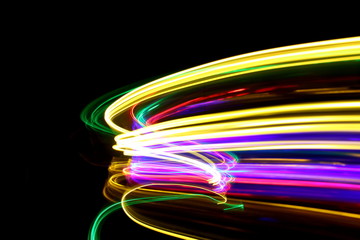 Long exposure photograph of neon multi colour in an abstract swirl, parallel lines pattern against...
